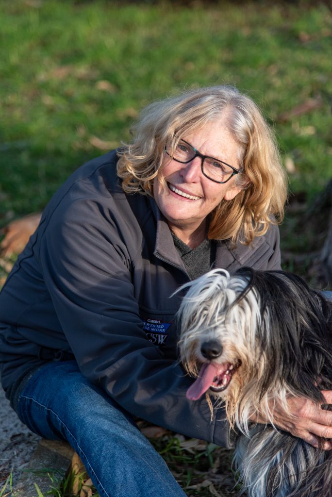 women smiles at camera patting a dog