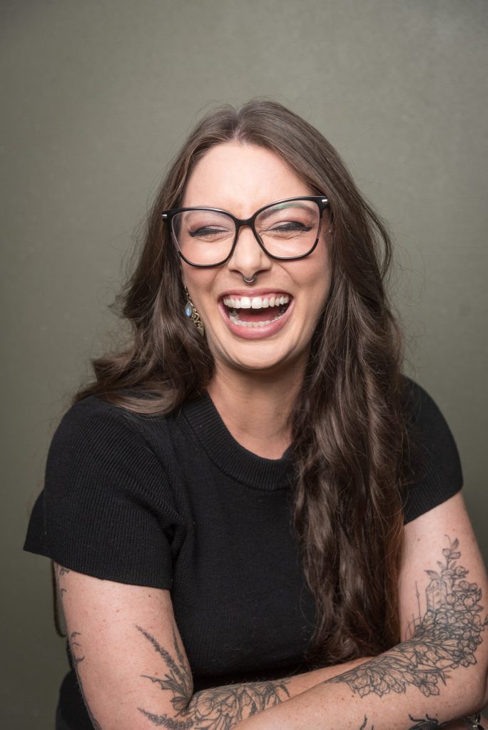 professional headshot of woman laughing on olive green background