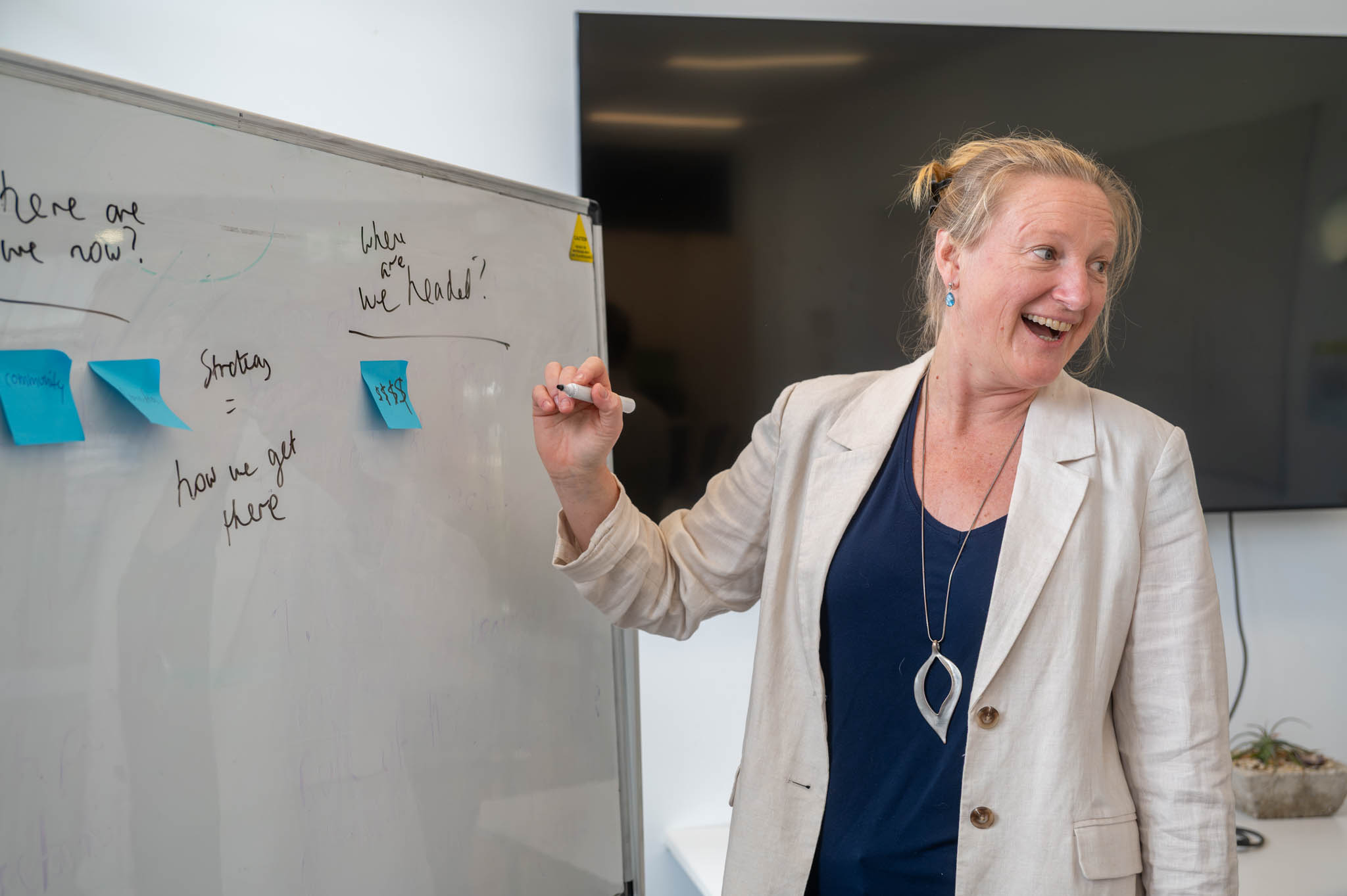 women at whiteboard laughs with audience